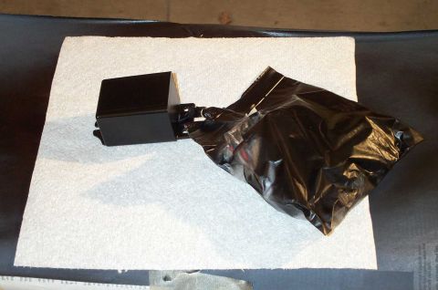 1998 Ford Crown Victoria - A black electronic component with attached wires is placed on a white paper towel, with a black plastic bag covering part of it.