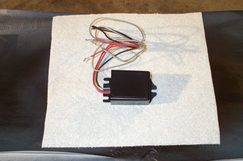 1998 Ford Crown Victoria - A black electronic module with attached wiring is shown on a white surface.