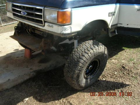 1991 Ford F-150 - Front view of a 1991 Ford F-150, modified with a large off-road tire and a custom bumper, resting on blocks.