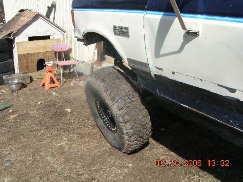 1991 Ford F-150 - Side view of a 1991 Ford F-150 truck with a large tire, parked outdoors near a doghouse.