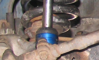1984 Ford Bronco - Close-up of a vehicle's suspension system, showing a blue bushing on a metal component.