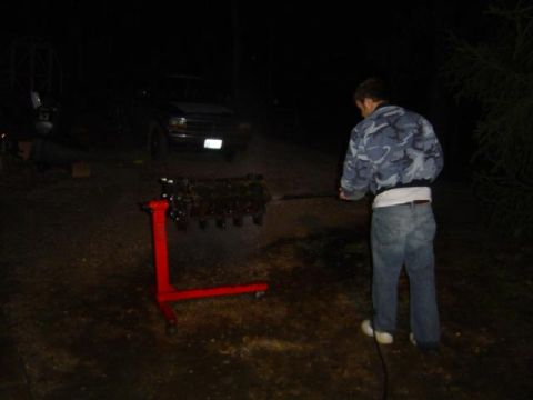 1979 Ford Bronco - A dark SUV is parked at night with an engine block on a stand in front of it.