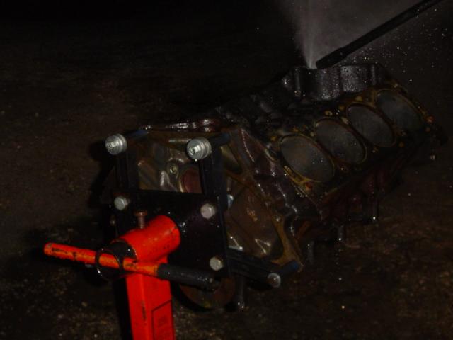 Engine block on red stand with water spraying on it