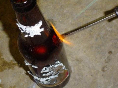 1979 Ford Bronco - A torch flame is applied to a bottle with peeling white material on its surface.