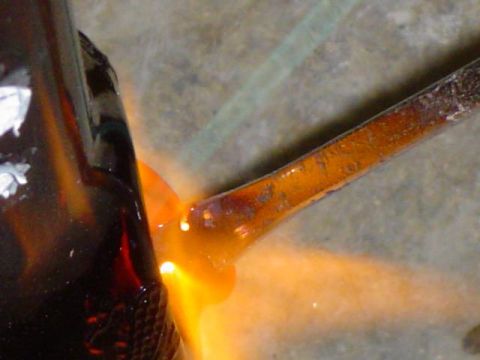 1979 Ford Bronco - A metal rod is being welded to a dark brown object, creating an orange glow and molten material.