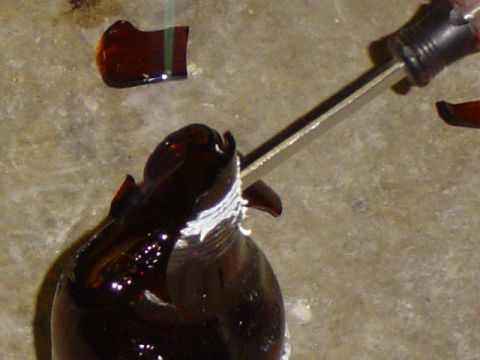 1979 Ford Bronco - A screwdriver is used to work on a broken amber bottle, with fragments scattered on the floor.