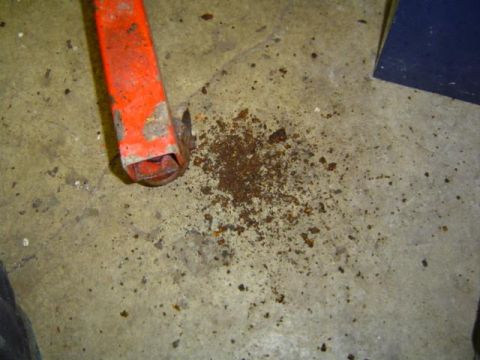 1979 Ford Bronco - A close-up view shows rust debris scattered on a concrete floor next to an orange jack.