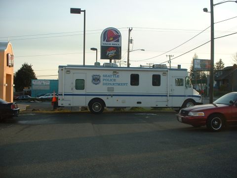 1999 Ford Crown Victoria - A Seattle Police Department truck is parked in a lot near a Taco Bell and Pizza Hut, with a red sedan nearby.