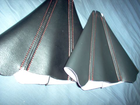 1994 Ford Probe - Two black leather shift boot covers with red stitching are shown against a blue fabric background.