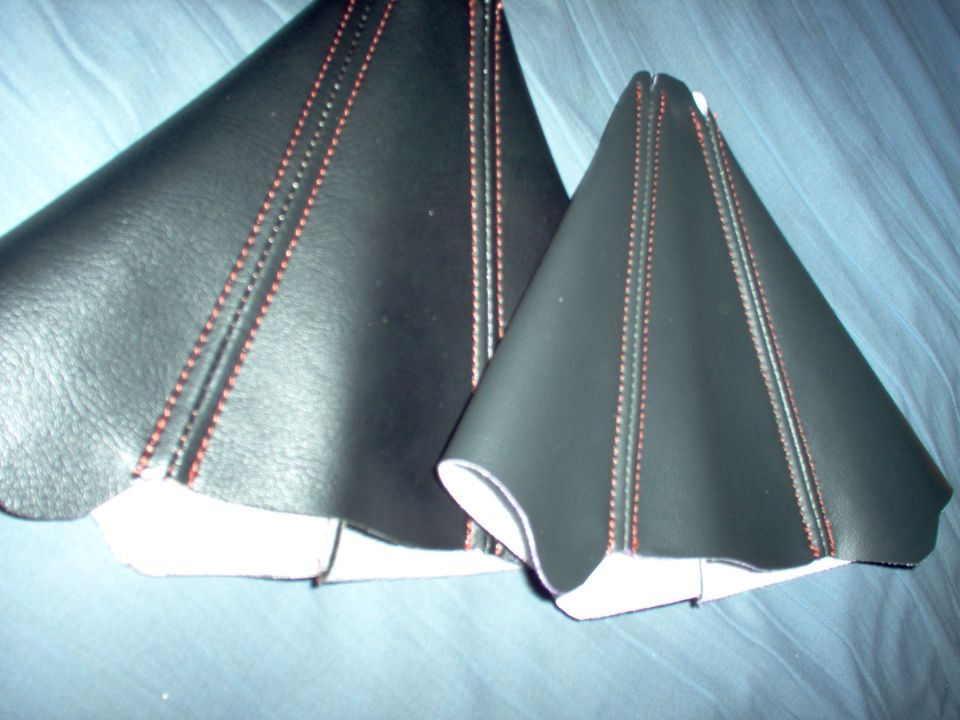 Two black leather shift boot covers with red stitching. One is larger than the other