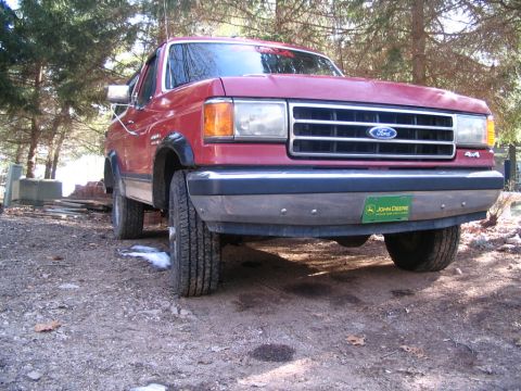 1989 Ford Bronco - Front view of a red Ford Bronco, likely a 1987 model, with a John Deere plate on the bumper.