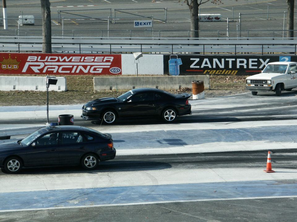 Black New Edge Mustang and dark Subaru Legacy in drag strip staging lanes