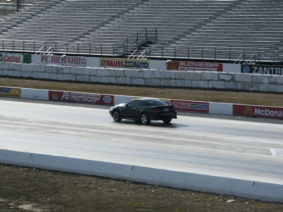 Dark Ford Mustang on a drag strip, seen from behind