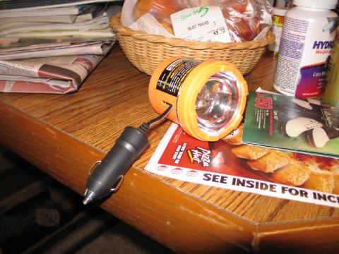 1995 Ford Bronco - A flashlight with a car adapter sits on a table next to a Pizza Hut flyer and other items.