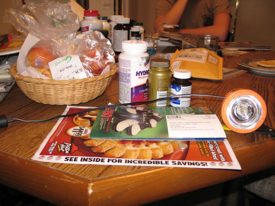 Table with a basket of peaches, pill bottles, mail, and an orange flashlight