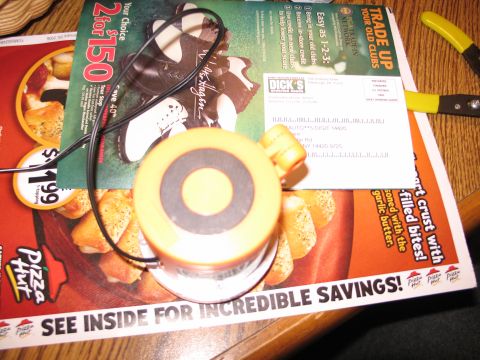1995 Ford Bronco - A yellow and black circular object with a wire is placed on top of various flyers and advertisements.