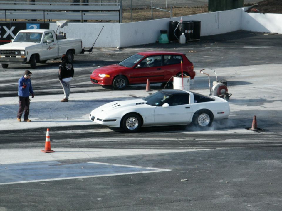 White Chevrolet Corvette C4 with a black roof, performing a burnout on a drag strip