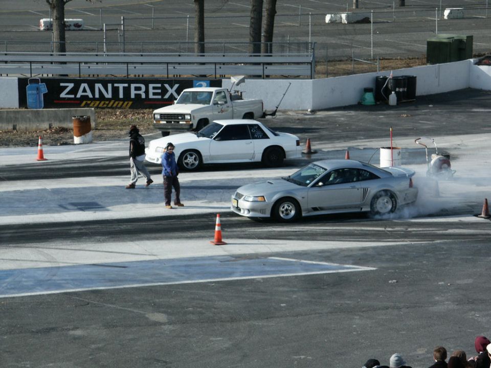Silver coupe doing a burnout on a drag strip