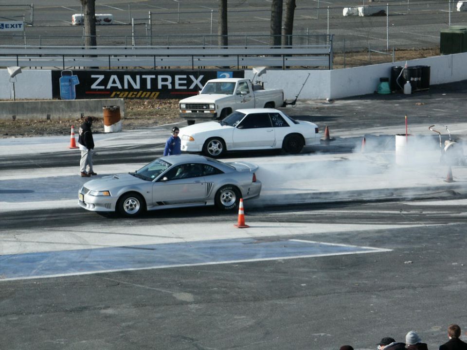 Silver New Edge Mustang doing a burnout in the drag strip water box