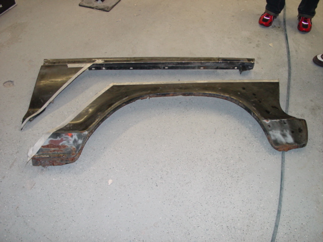 Two removed fender sections, one with an arch, laid on a concrete floor