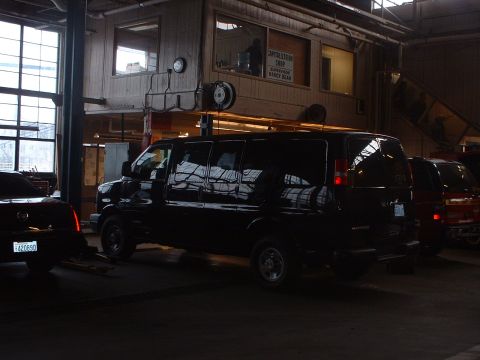 1999 Ford Crown Victoria - A black van and a dark sedan are parked inside a garage with a visible loft office area above.