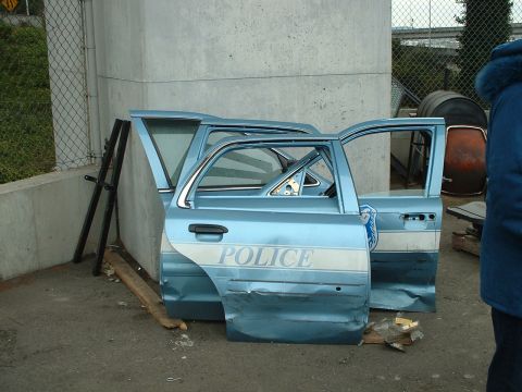 1999 Ford Crown Victoria - Removed police car doors lie on the ground, showing damage and the word "POLICE".