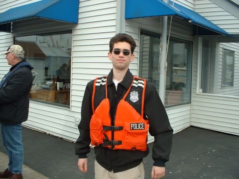 1999 Ford Crown Victoria - A man stands outside a building wearing a life vest labeled "POLICE".