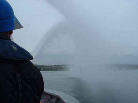 1999 Ford Crown Victoria - A person on a boat sprays water into the air on a cloudy day.