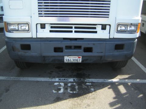 1990 Ford Bronco - close-up of a white cabover truck's lower grille, dual headlights and bumper, showing California plate 9A43087 over a 305 stall marking.
