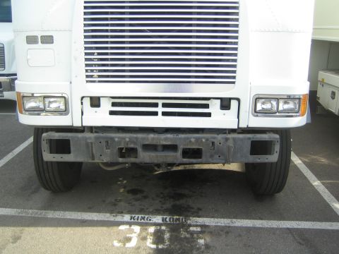 1990 Ford Bronco - close-up of a white cabover semi's lower grille, headlights and stripped bumper above a KING KONG 305 painted stall marking.