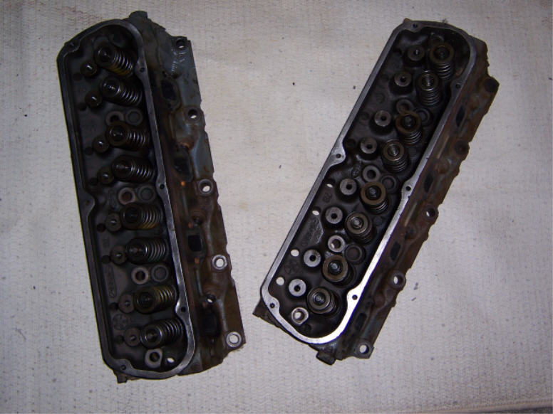 Two used cylinder heads with valve springs installed, lying on a white cloth