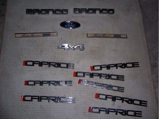 Chrome Bronco, Ford oval, Eddie Bauer, 4x4 and many CAPRICE emblems laid on carpet