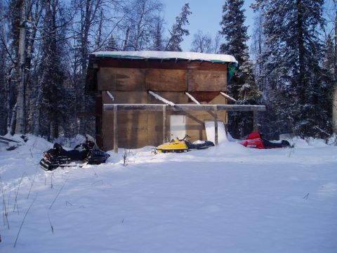 2000 Ford E350 - Winter scene with snowmobiles and a shed in a snowy, wooded landscape.