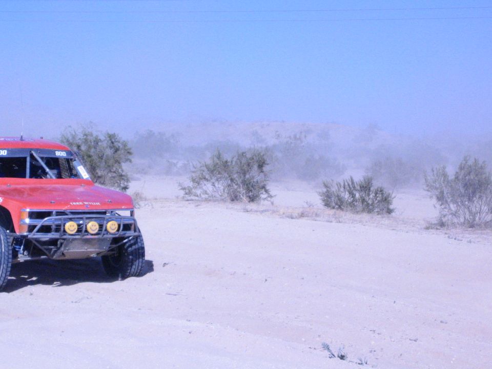 Red off-road race truck number 800 on a sandy desert course