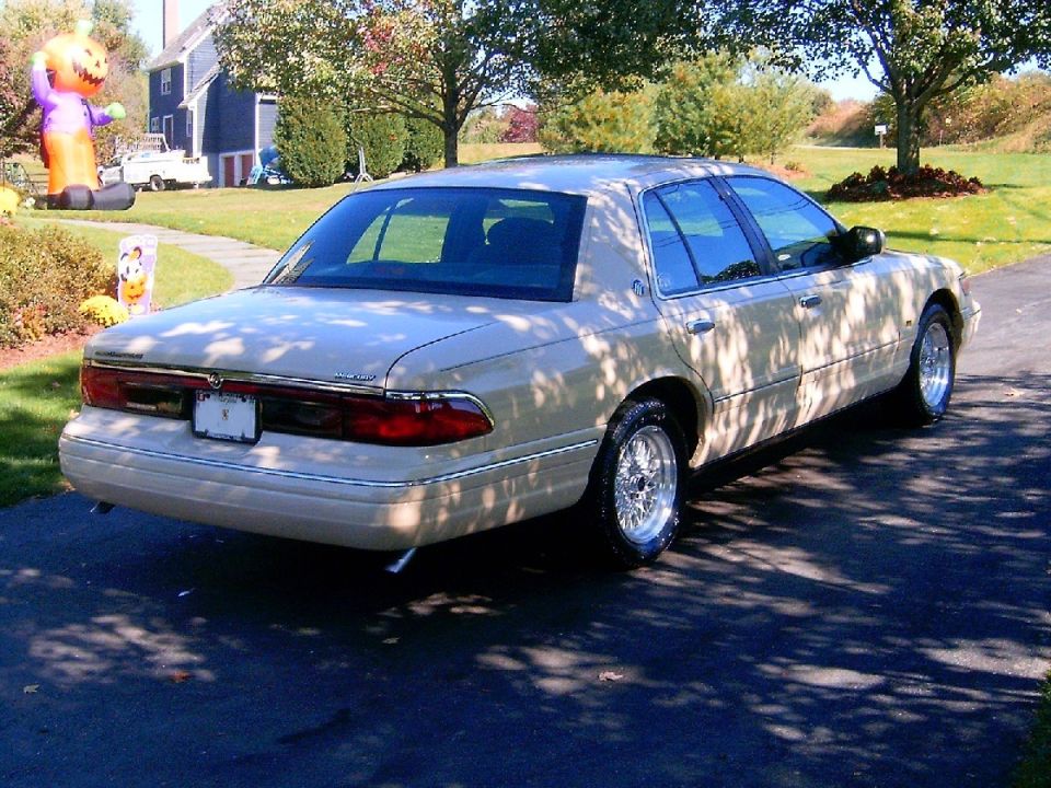 Gold Mercury Grand Marquis rear three-quarter near an inflatable pumpkin and barn