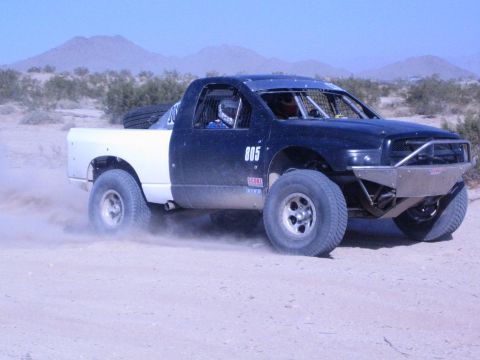 Black off-road race truck number 805 with white bed in the desert