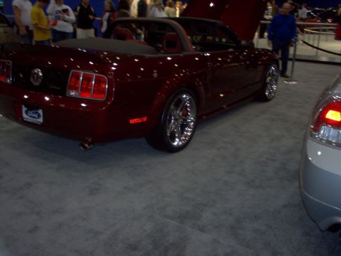 1970 Ford Ranchero - A red convertible is parked indoors next to another vehicle.