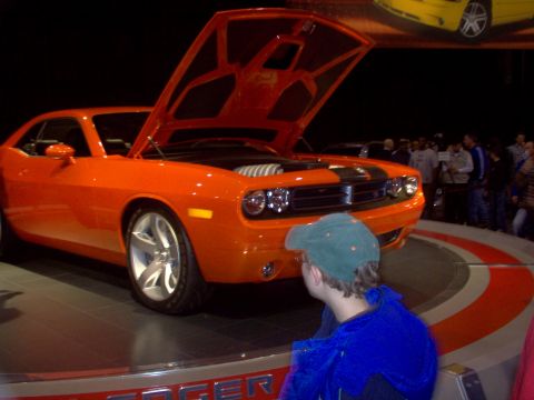 1970 Ford Ranchero - Orange Dodge Challenger on display with hood open, viewed from the front.