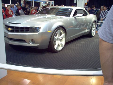 1970 Ford Ranchero - A silver Chevrolet Camaro concept car is displayed on a black mat with a crowd of onlookers.