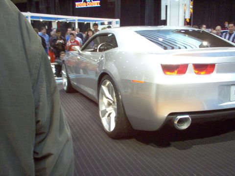1970 Ford Ranchero - A silver concept car is displayed indoors, with people in the background and a watermark at the bottom right.