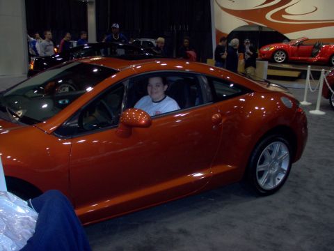 1970 Ford Ranchero - A person sits inside an orange coupe at what appears to be a car show.