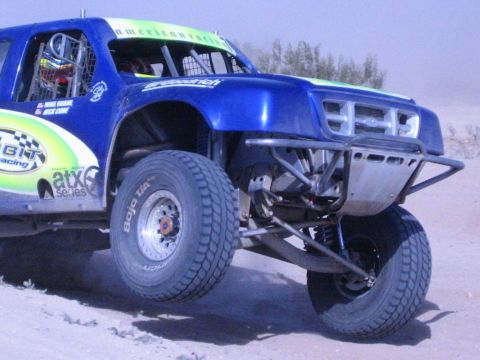 Close view of a blue off-road race truck's tube-frame front suspension