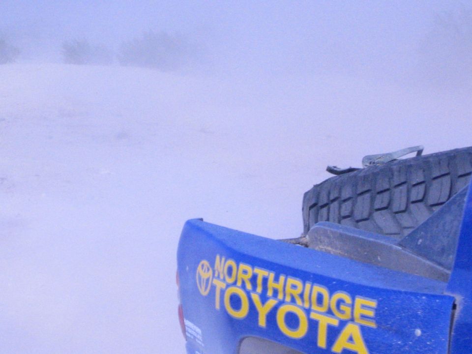 Rear corner of a blue race truck with Northridge Toyota decal in dust
