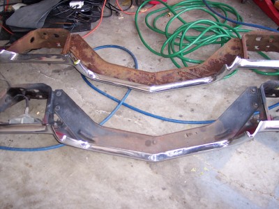 1972 Ford Ranchero - Two car bumpers are shown, one with significant rust, on a concrete surface with coiled hoses in the background.
