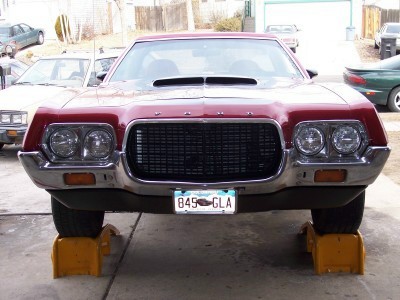 1972 Ford Ranchero - The front grille and headlights of a red 1972 Ford Gran Torino are visible as it sits on jack stands.