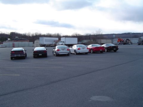 2002 Chevrolet Camaro - Several cars are parked in an outdoor lot, including a red 2002 Chevrolet Camaro visible from the rear.