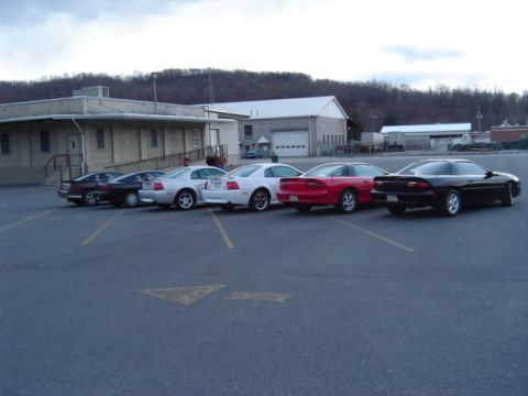 2002 Chevrolet Camaro - A group of cars, including two Chevrolet Camaros, are parked in an outdoor lot.