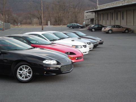 2002 Chevrolet Camaro - Several cars are parked in a lot, including a black 2002 Chevrolet Camaro in the foreground.