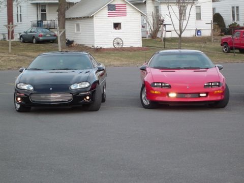 2002 Chevrolet Camaro - Two Chevrolet Camaros, one black and one red, are parked facing the camera.
