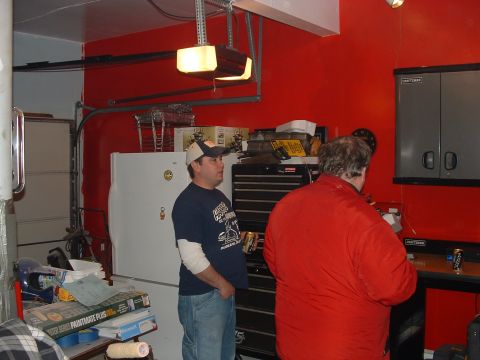1978 Chevrolet C/K Pickup - Two men stand in a garage with red walls, tool chests, and a refrigerator visible.